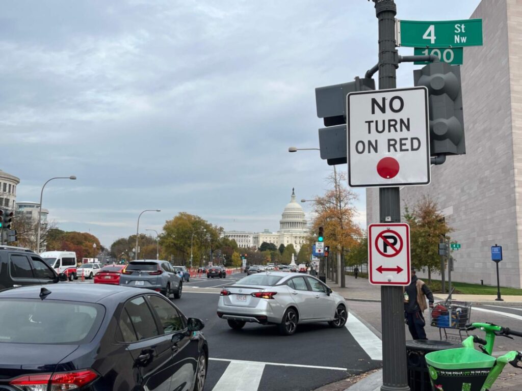 Cars drive past a No Turn on Red sign on Pennsylvania Avenue at 4th Street NW in Washington, DC.
