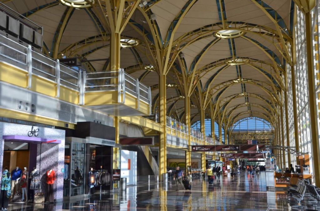 Travelers roll suitcases through the soaring, shop-lined hall of Terminal B at Ronald Reagan National Airport in Washington DC.