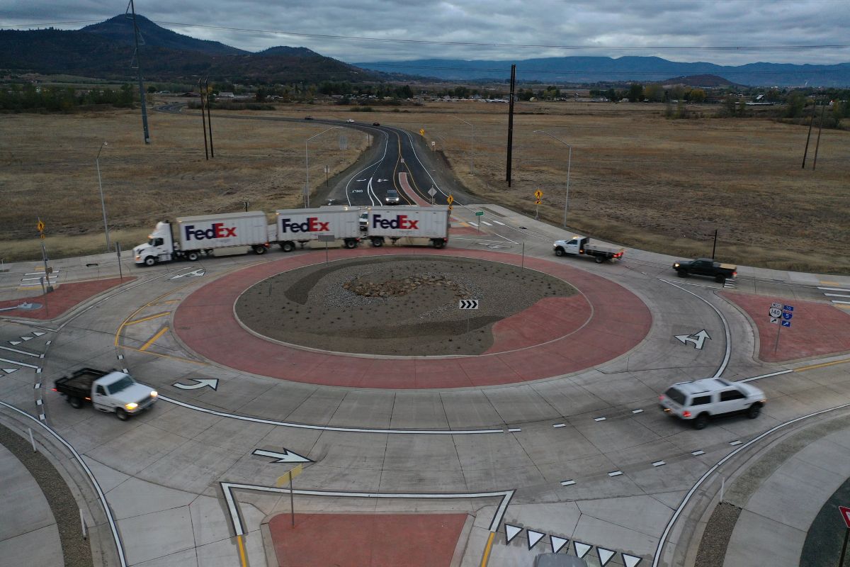 Aerial view shows a three-trailer FedEx truck and a few smaller trucks moving through an Oregon roundabout.