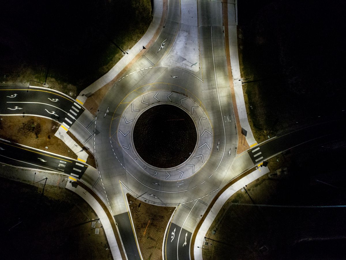 Aerial view at night shows bright lights illuminating a roundabout.