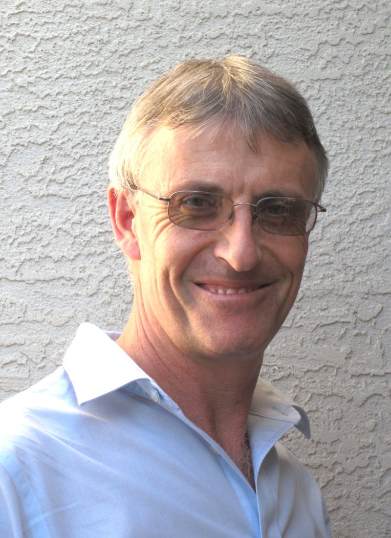 David Jones smiles while facing the camera as he stands against a textured white background.