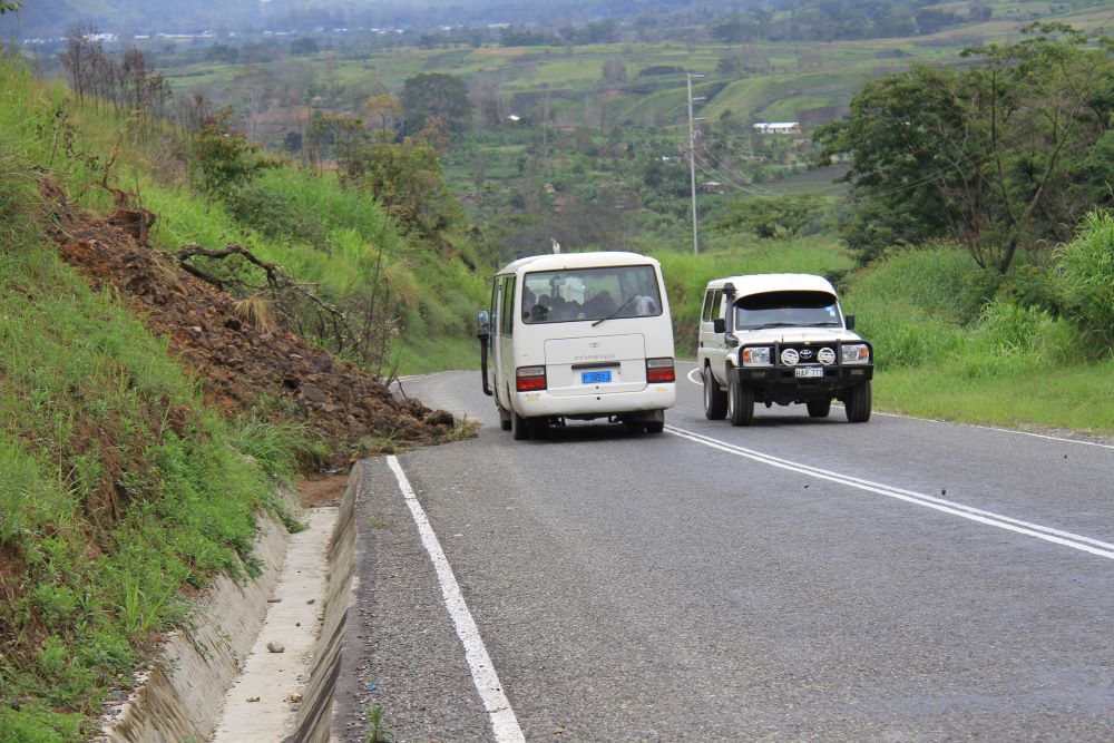 Landslide near two white vehicles on low-volume road