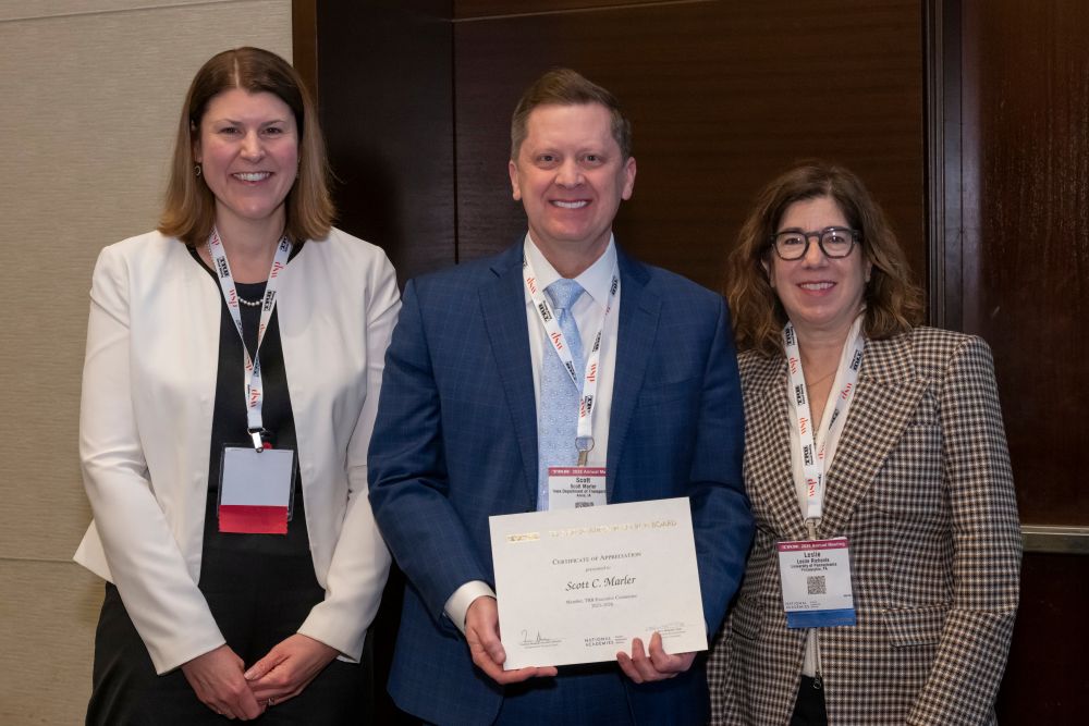 Victoria Sheehan, Scott Marler, and Leslie Richards stand together as Scott Marler holds a certificate.