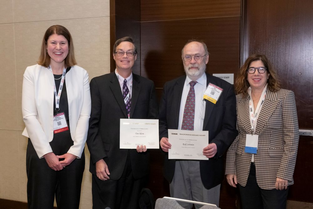 Victoria Sheehan, Timothy Klein, Rolf Schmitt, and Leslie Richards stand together as Timothy Klein and Rolf Schmitt hold certificates.