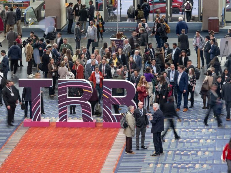 Crowd Near TRB Sign A large crowd of TRB Annual Meeting attendees gather around or walk by large letters T R B near the entrance of the Walter E. Washington convention center in DC.