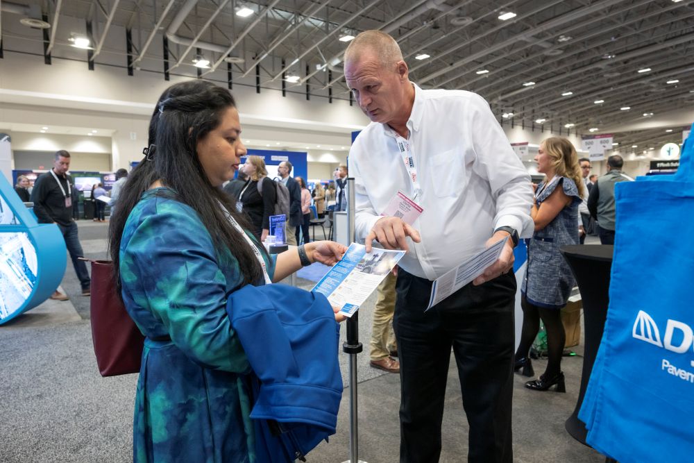 Charles Moore points to a brochure while speaking with Salma Sultana, who holds a jacket.