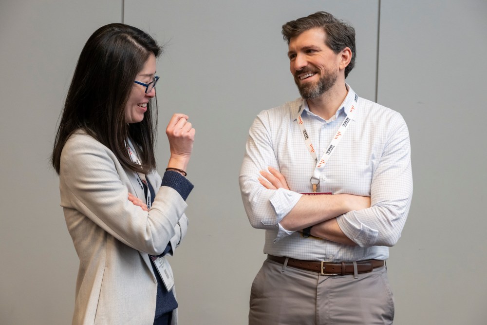 Grace Wang and Matthew Antonelli, in formal wear with I D cards, stand and smile while having a discussion.