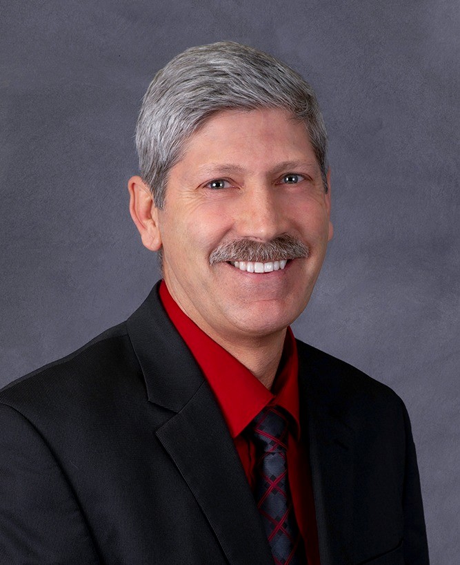 Joel M. Jundt, in formal wear, faces the camera and smiles.