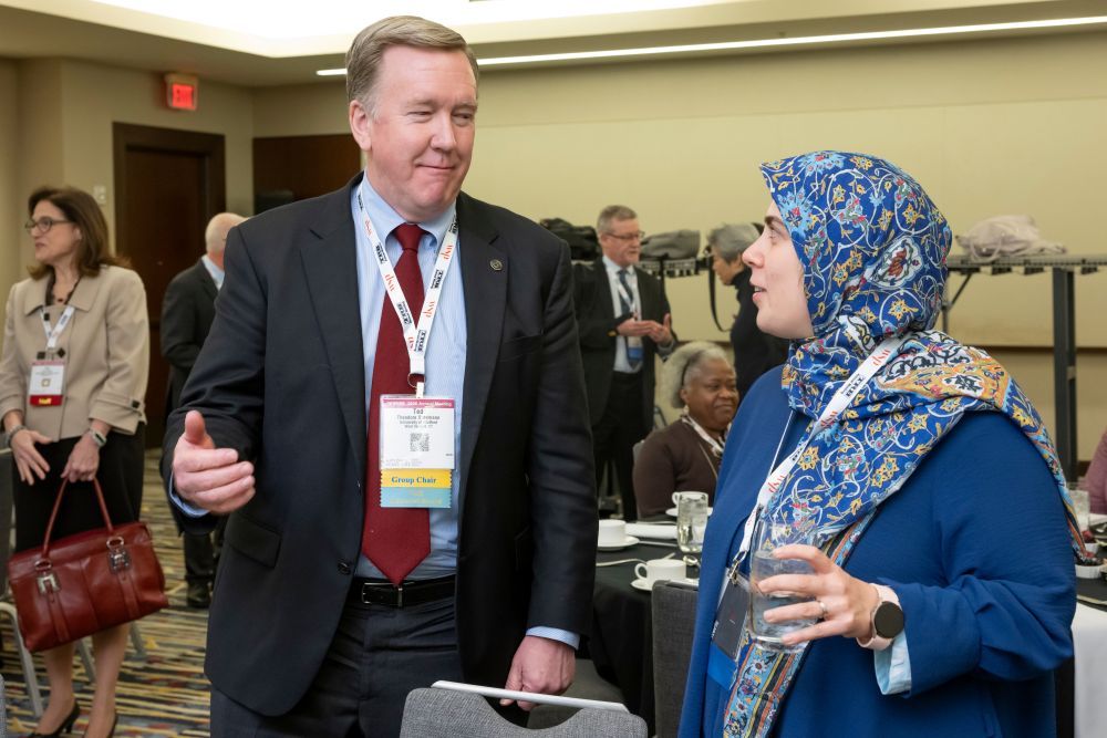 Ted Sussmann gestures while speaking with Niloo Parvinashtiani, who holds a glass.
