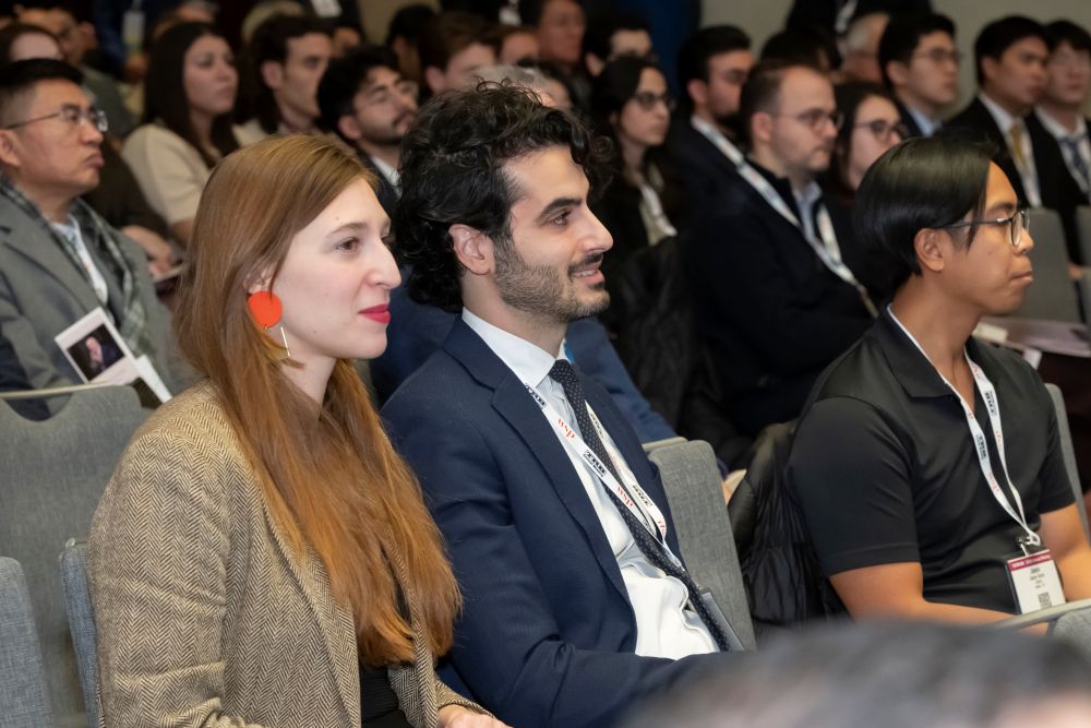 An audience listens while sitting in rows at Hani S Mahmassani's memorial service. Two people in the front row smile.