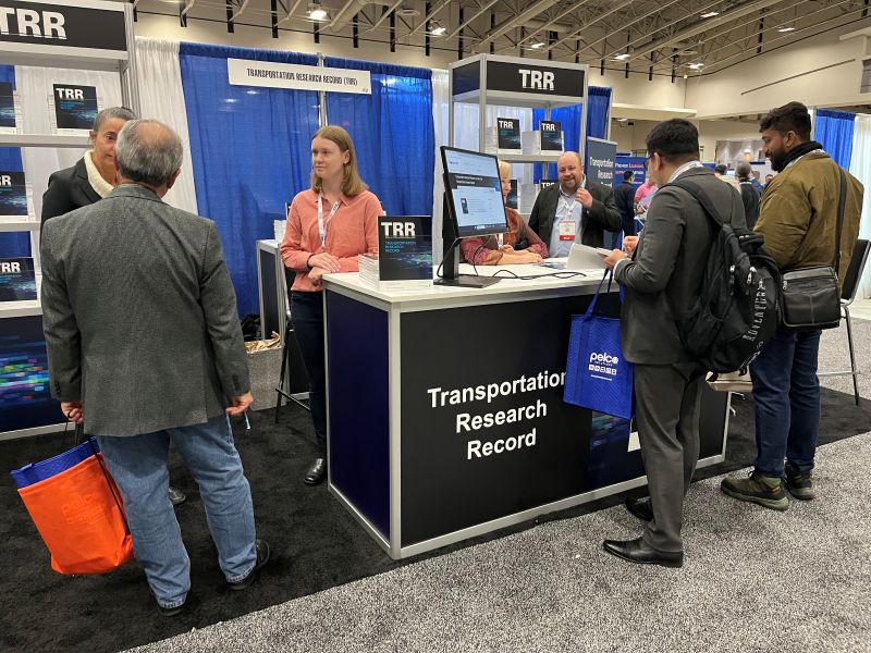 Staff at the Transportation Research Record booth exchange information with attendees.