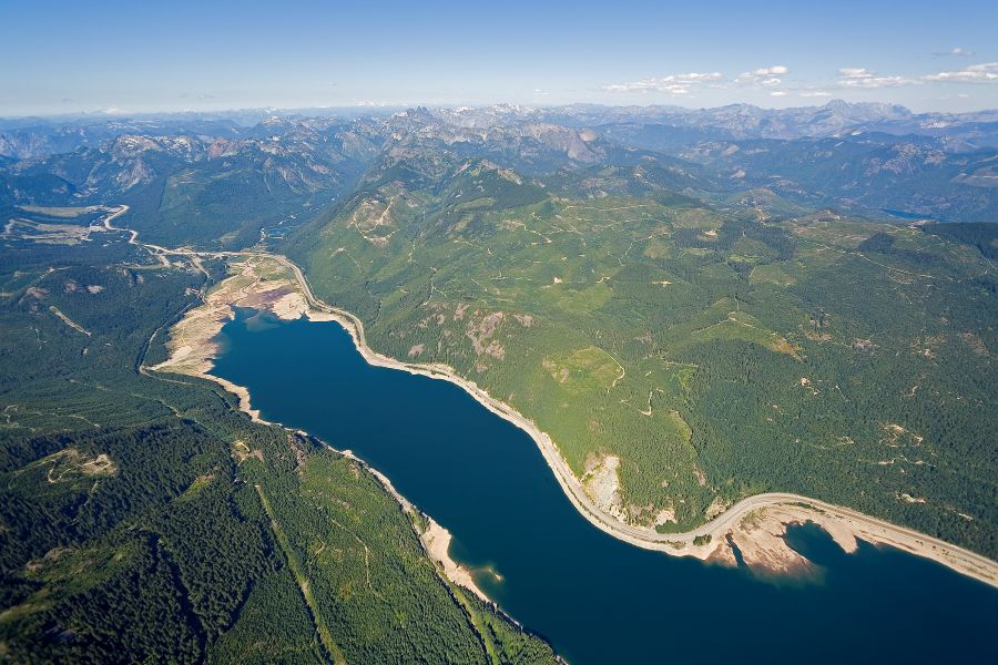 An aerial view in Washington State shows the Cascades mountain range, forested valleys, and a large lake, with the Interstate 90 corridor extending along the lake and stretches beyond.