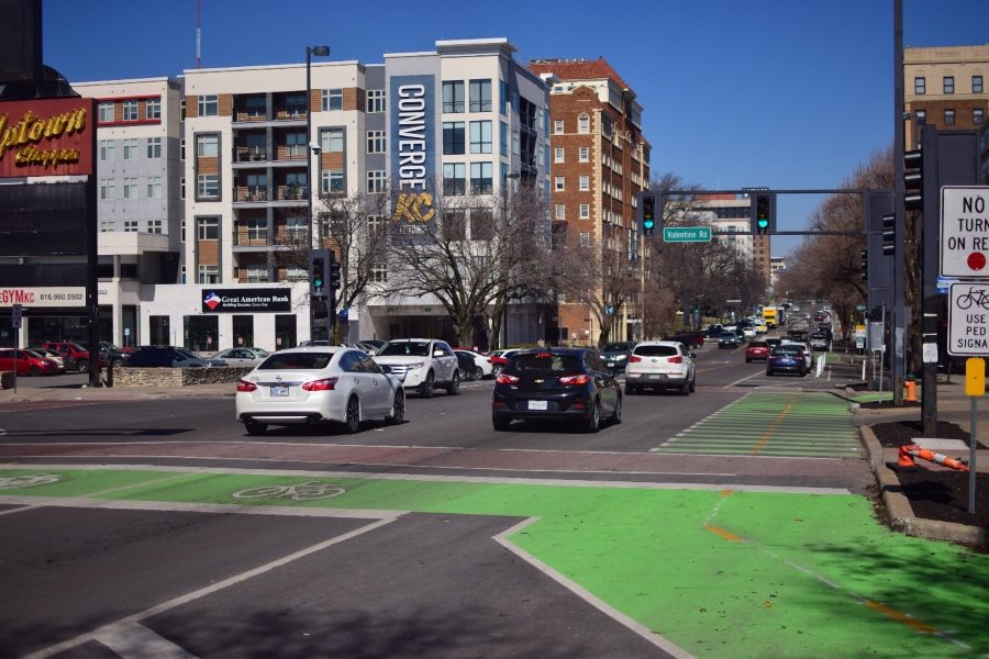 An urban street has three traffic lanes, bike lanes marked across the intersection, and a painted crosswalk.