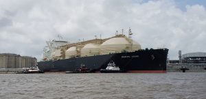 A large liquified natural gas (L N G) carrier named Marvel Crane is guided by tugboats as it moves near a port facility in Louisiana.