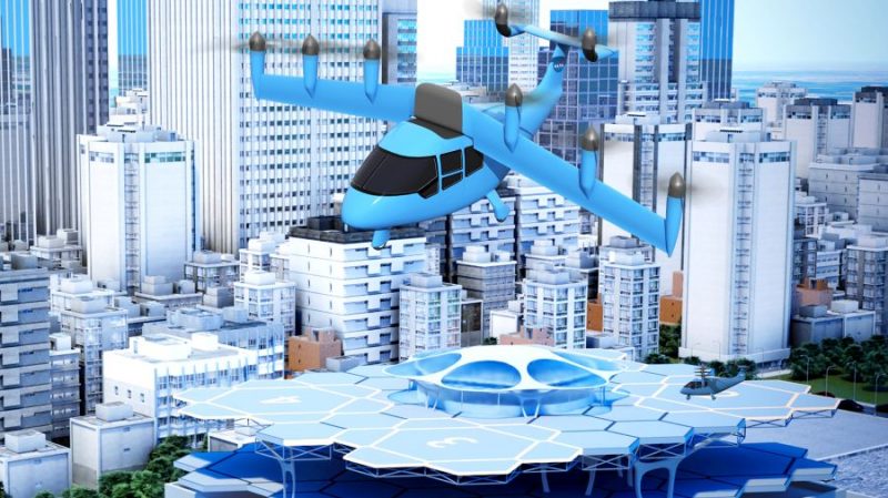 A concept rendering shows a large aircraft with three vertical propellers on each wink and two on the tail flying above a city with multistory buildings and a rooftop landing area.