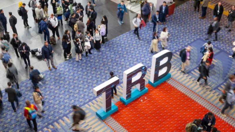 Attendees gathering or walking past the TRB sign at the 2025 TRB Annual Meeting.